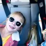 Children in a car packed for a road trip.